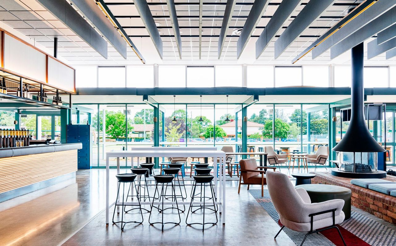 Indoor fireplace and low brick wall play focal point in restaurant, while viweing out to bowling green beyond the alfresco dining